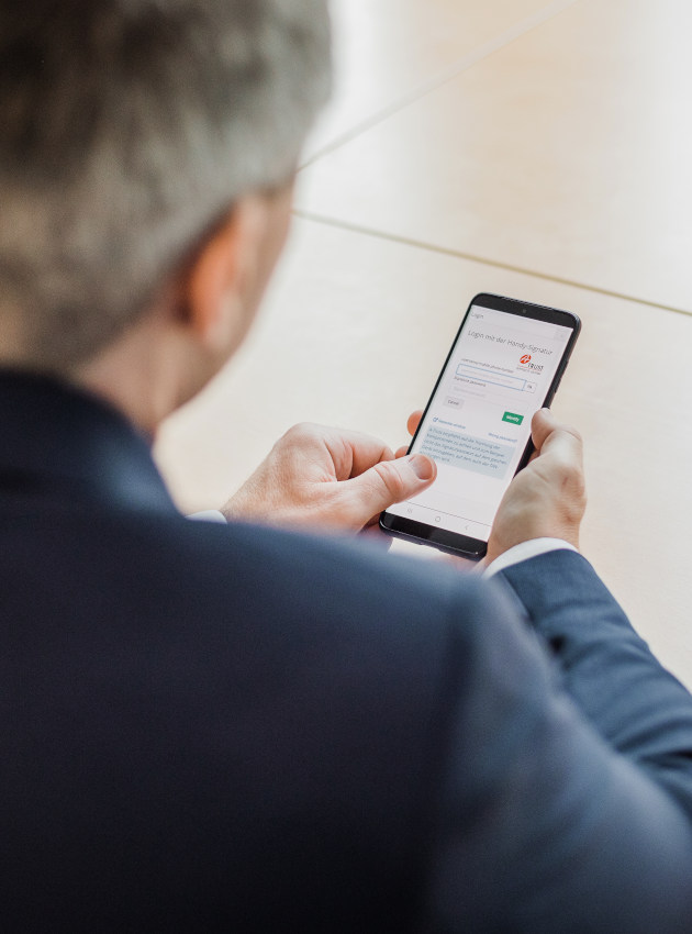 A businessman signs a document with his smartphone.
